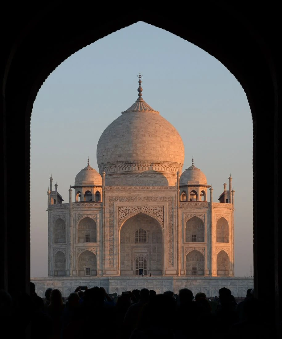Taj Mahal framed by a gateway arch at sunrise